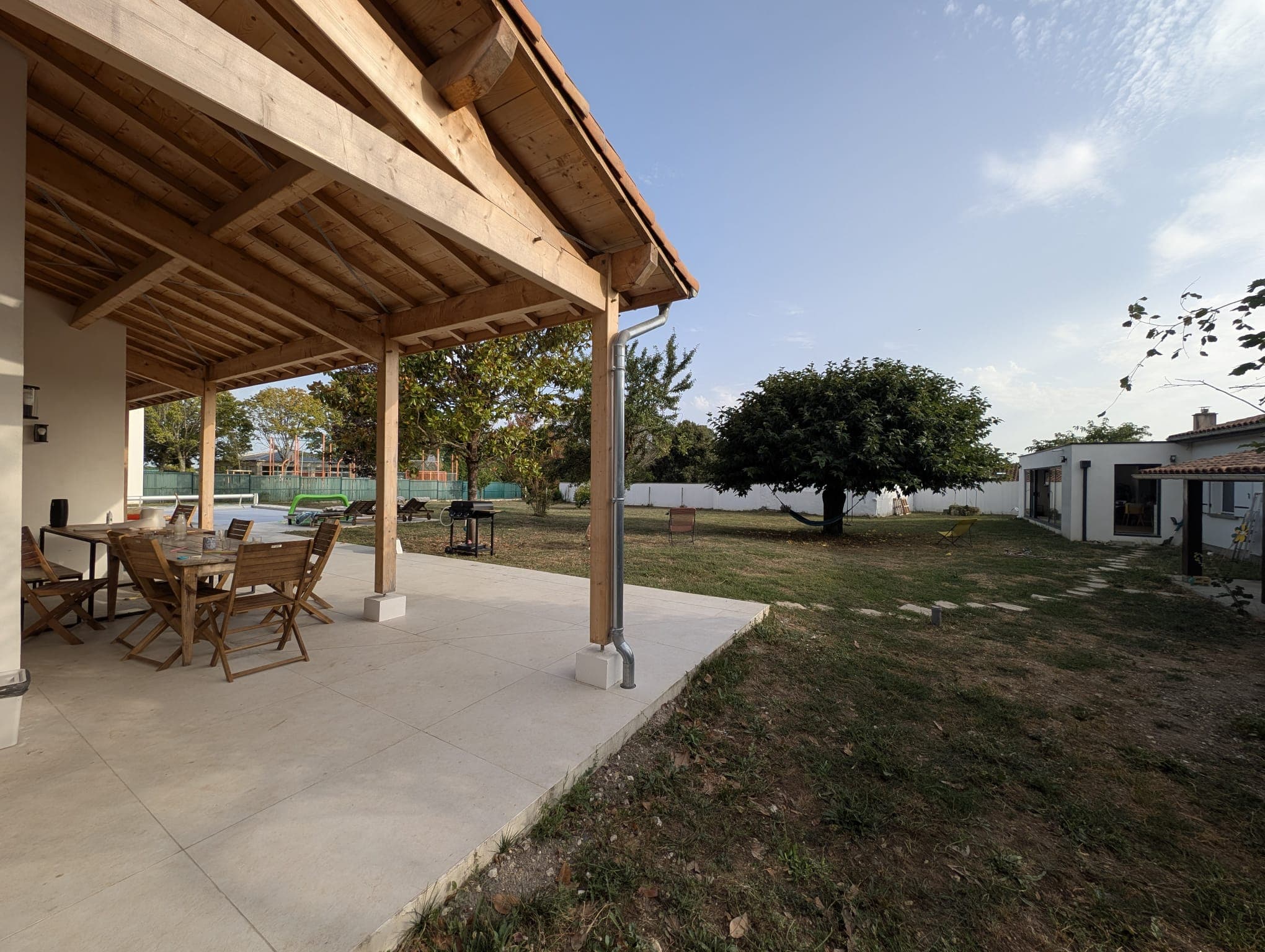 Terrasse couverte avec table dressée pour quinze personnes, vue sur la piscine